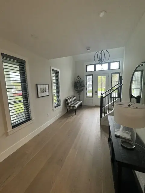 Sheer shadings on tall windows along a bright front hallway