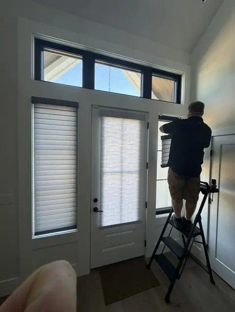 Installer on a step ladder fitting a shade above a front door