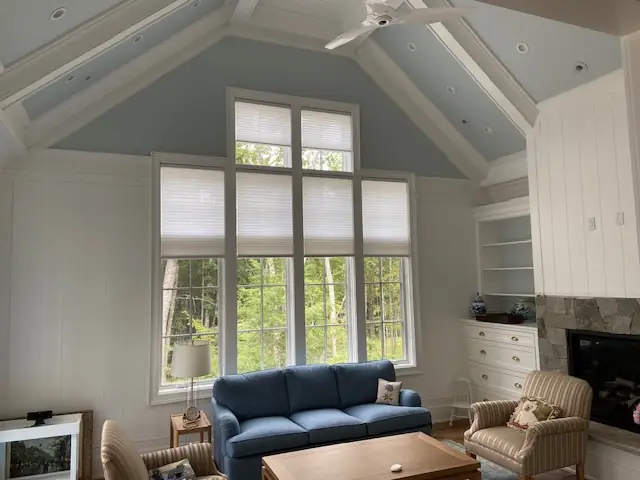 Top-down cellular shades on tall living room windows under a vaulted ceiling