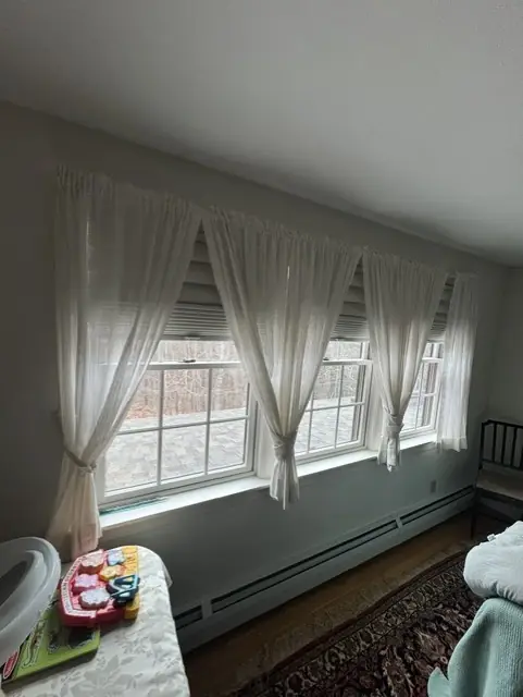 Sheer curtains tied back over shades along a row of sunroom windows